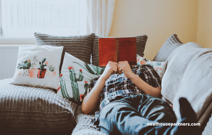 Man relaxing on sofa with book 