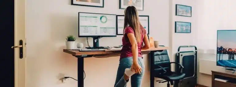 Woman stretching while using standing desk in a home office
